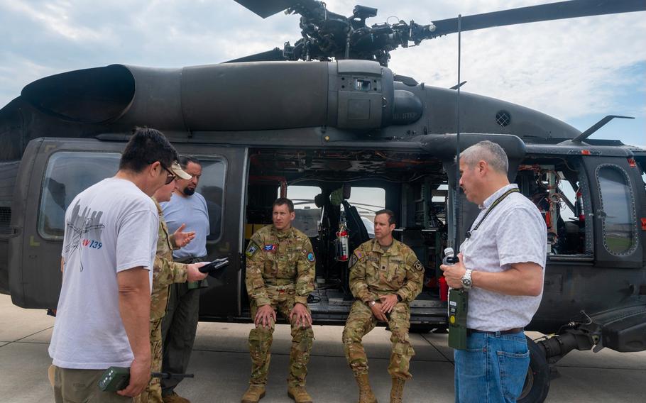 People speak to airmen sitting in a helicopter.