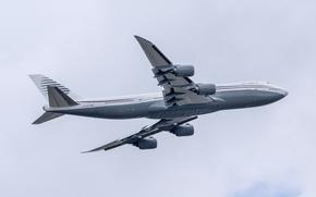 A Boeing ariliner, seen from below, flies in the air.
