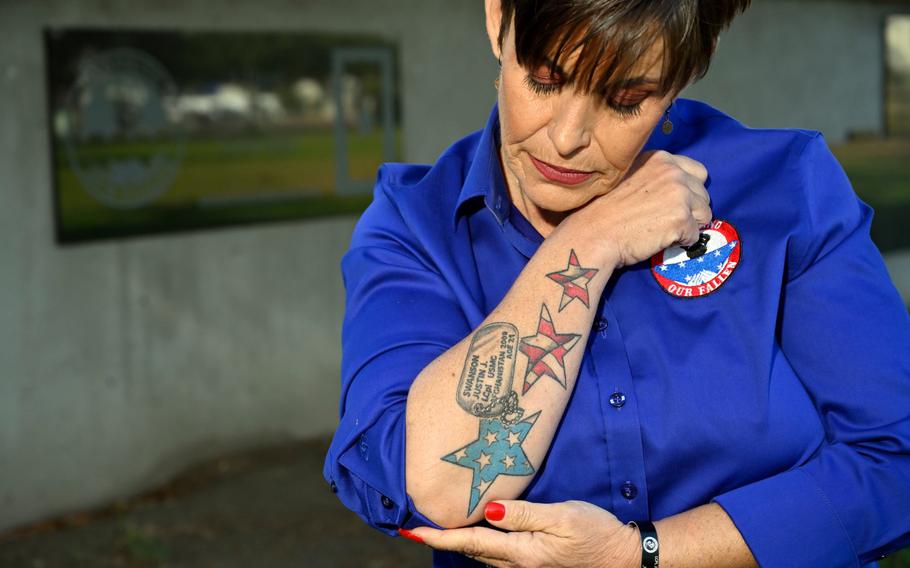 Laura Herzog, founder of Honor Our Fallen, shows her tattoo for Justin Swanson, at the memorial wall in Rosie the Riveter Park in Long Beach, Calif., on Dec. 15, 2021. Swanson’s family was the first helped by Herzog’s organization. Since 2011, she has helped more than 1,000 families who have lost a service member loved one in combat, a training accident or suicide.