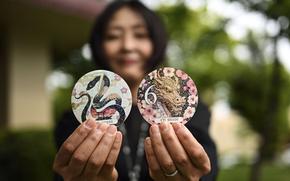A woman holds out car sticker decals featuring colorful animal designs.