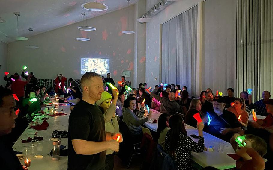 Glow sticks held by mourners light up a dim room. 
