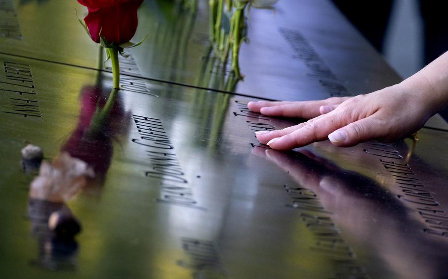 Hands touch the names of people who were killed during the attacks on the World Trade Center on Sept. 11, 2001, as families gather at the National September 11 Memorial in New York on the 20th anniversary of the attacks, Saturday, Sept. 11, 2021.