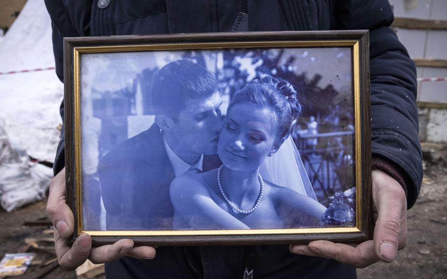 Serhiy Kaharlytskiy holds a wedding photo taken from the rubble of his home.