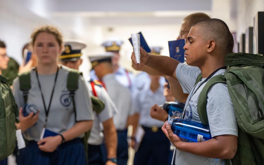 Coast Guard Academy cadets stand with their belongings