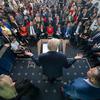 Reporters listen as the president, with his back to the camera, answers questions.