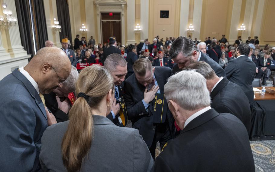 A group of people huddle in a circle with their heads down.