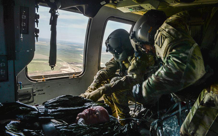 Sgt. 1st Class Christopher Carney, a paramedic with the 23rd Aviation Regiment, and his flight engineer simulate treatment on Army Brig. Gen. Clinton Murray near Bordusani, Romania, on June 6, 2023. The simulation was part of Exercise Saber Guardian.