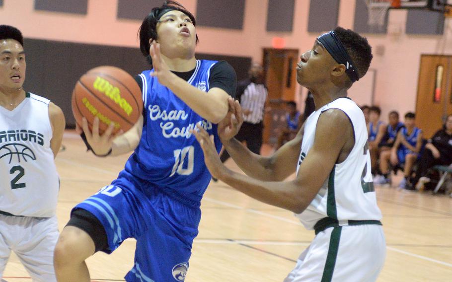 Osan's Dash DeSilva puts up a shot against Daegu's Philip Turner during Friday's Korea boys basketball game. The Cougars edged the Warrriors 73-70.