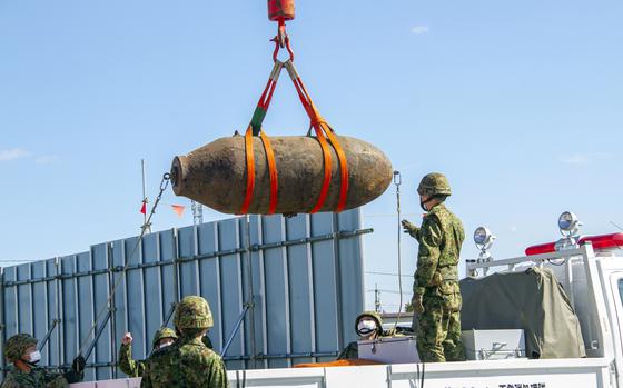 Japanese soldiers remove a defused unexploded bomb from World War II out of a construction site in Kuwana city, Japan, Sunday, Feb. 5, 2023.