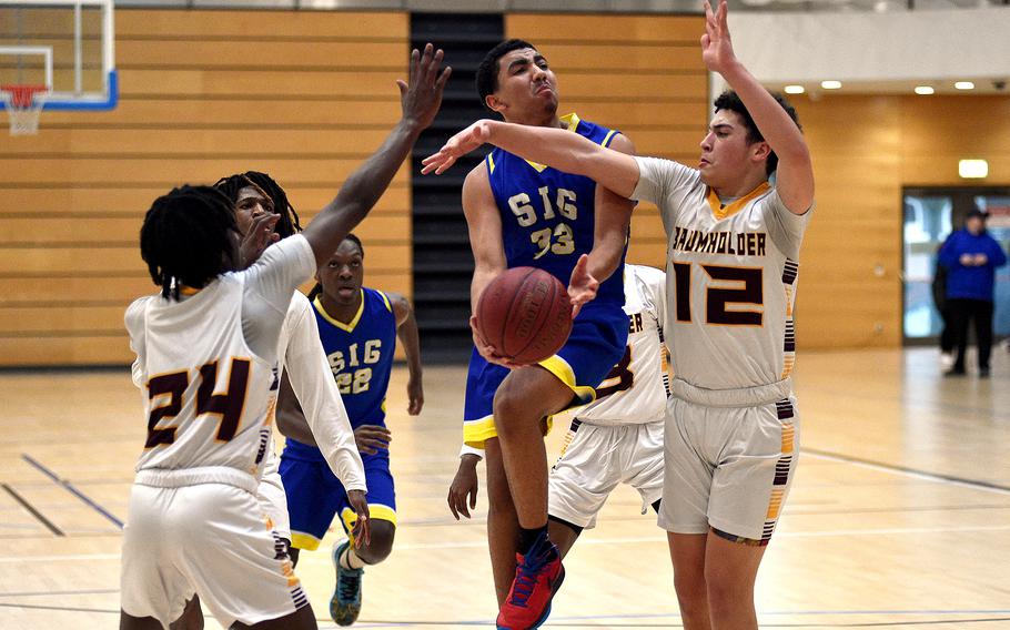 Sigonella sophomore Jacob Maloney fights through Baumholder defenders Gregory Makubuya, left, and Keryel Badillo during pool-play action of the DODEA European basketball championships on Feb. 14, 2024, at the Wiesbaden Sports and Fitness Center on Clay Kaserne in Wiesbaden, Germany.