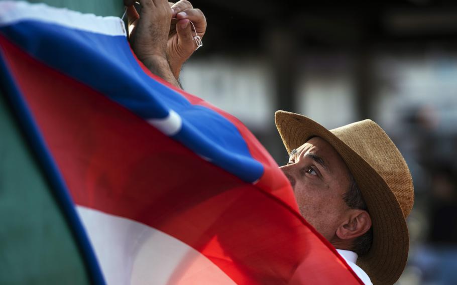 Middle school art teacher Emilio Baez hangs a Puerto Rican flag during a Hispanic Heritage Month celebraton at Marine Corps Air Station Iwakuni, Japan, Oct. 13, 2023. 