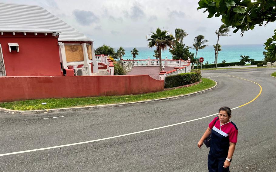 A woman walks by a closed restaurant with boarded up windows in Horseshoe Bay, Bermuda, as Hurricane Fiona churned towards the Atlantic island as a powerful Category 4 storm on Sept. 22, 2022.