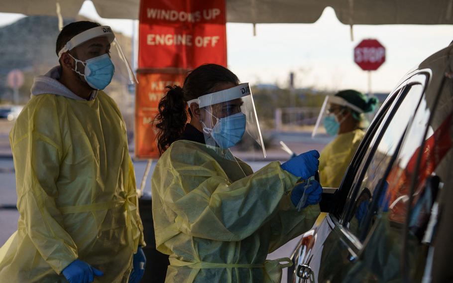 Health care worker Azucena Estrada, center, collects nasal swab samples at a drive-thru COVID-19 testing site in El Paso, Texas, on Jan. 12, 2022.