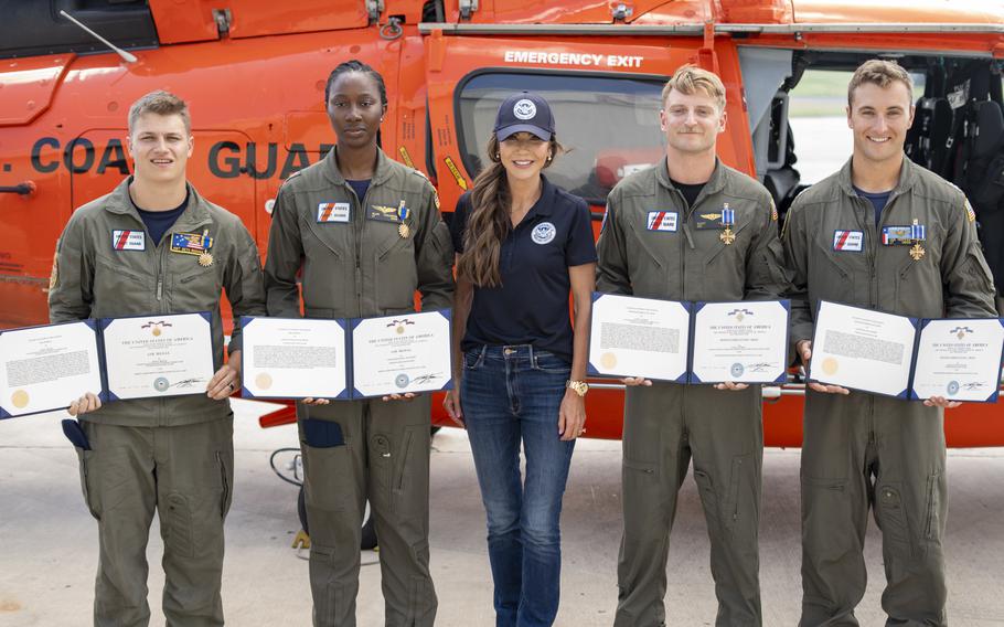 Kristi Noem poses with four Coast Guard aircrew members