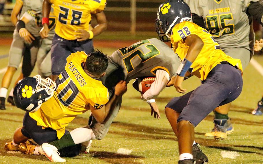 Despite losign his helmet, Guam High's Terrell Rosario brings down John F. Kennedy's Irwin White as Panther teammate Robert Ellis looks to help.