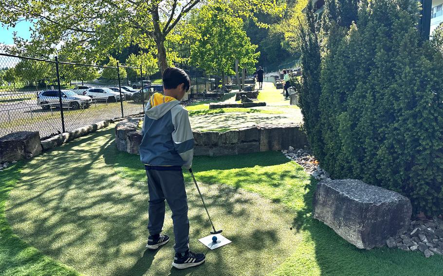 A child prepares to putt on a miniature golf course.