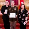 Martin and his parents hold the medals with flags behind them.