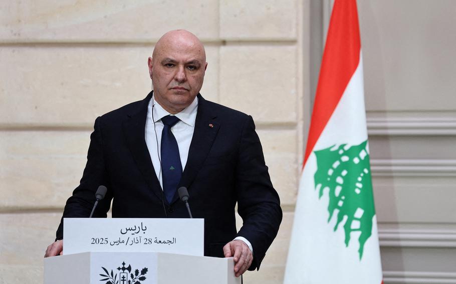 The president of Lebanon in a suit at a white podium.