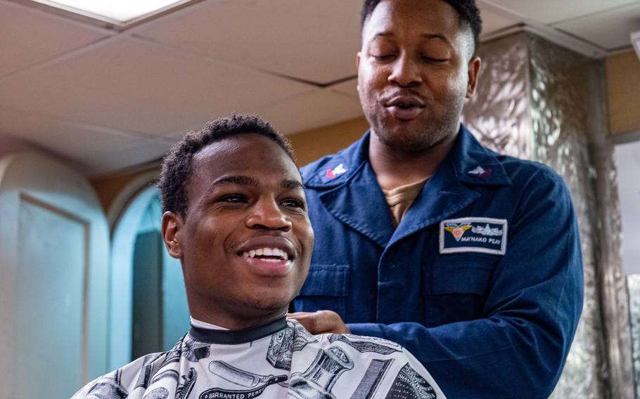 Aviation Boatswain’s Mate Airman Reginald Martin, Jr., a native of Shreveport, La., left, sits down for a haircut from Retail Services Specialist 2nd Class Ma’Nako Peay, a native of Lancaster, S.C., in the barber shop of Nimitz-class aircraft carrier USS Carl Vinson on July 3, 2021. 
