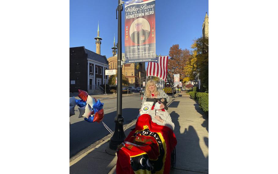 Brenda Banaszek holds onto the wheel chair of her father, Marine veteran Henry Banaszek, as the two stand beneath a Hometown Heroes banner hoisted in Wilkes-Barre, Pennsylvania.