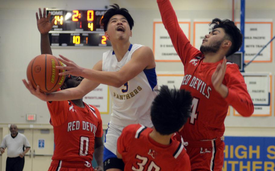 Yokota's Dylan Tomas drives through Nile C. Kinnick defenders Darius Scott and Oliver Chilton and plows into Red Devils guard Adrian Tagalog during Thursday's DODEA-Japan boys basketball tournament game. Tomas was called for an offensive foul on the play. The Red Devils won 63-50.