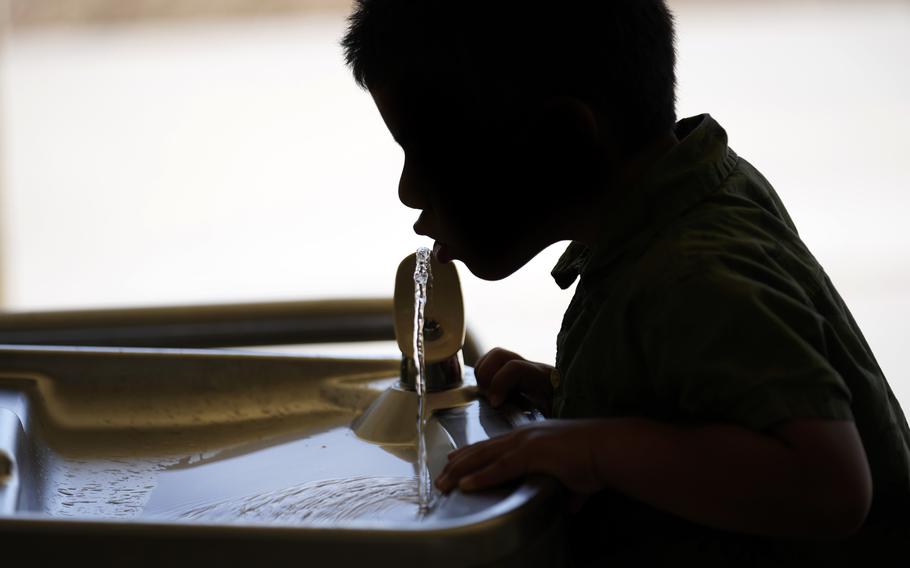 A kid drinks from a water fountain 