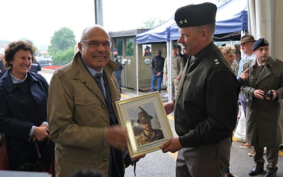 Franco Miotto and U.S. Army Maj. Gen. Todd Wasmund hold up a portrait of Cpl. Matteo Miotto on May 7, 2024, in Longare, Italy. The Longare base, which hosts the U.S. Army's 207th Military Intelligence Brigade (Theater), had been without an official name until Tuesday, when it became Caserma Matteo Miotto.