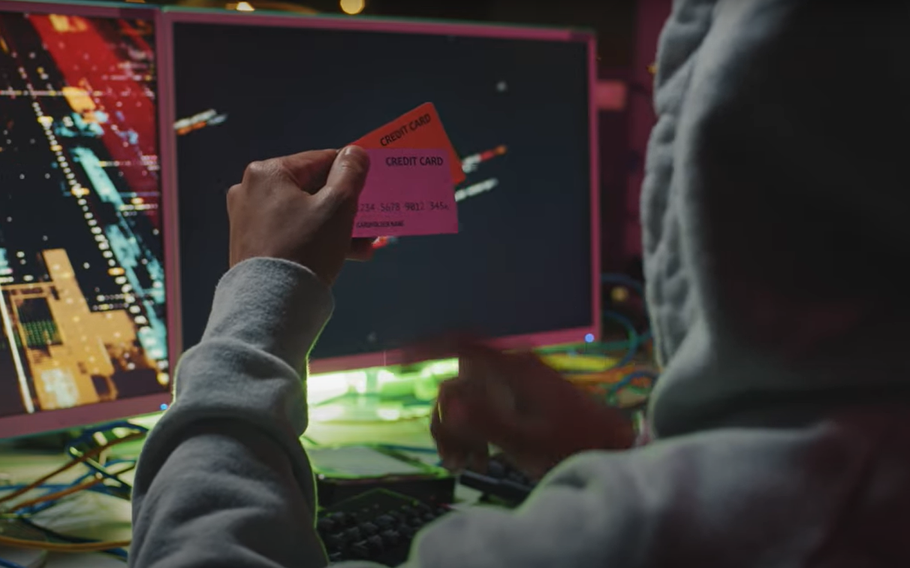 A person holding two credit cards in front of a computer