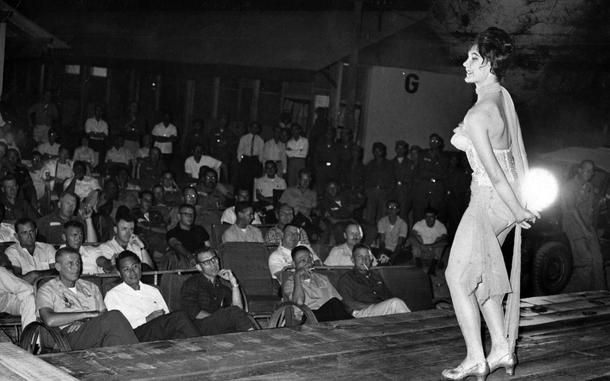 Hed: Soft shoe dancing, 1963

Quang Nai, South Vietnam, April 1963: Geri Griffin, a softshoe dancer, dances on stage as men of Military Assistance Advisory Group and members of the U.S. 25th Infantry Division gaze at her. Her stage? The top of two trailers, with an outdoor spotlight to illuminate her act.
Soft shoe dancing is - according to Encyclopedia Brittanica - "a relaxed, graceful dance done in soft-soled shoes and made popular in vaudeville." Sadly, Stars and Stripes' archivists were unable to find any information on Ms. Griffin.

Looking for Stars and Stripes’ historic coverage? Subscribe to Stars and Stripes’ historic newspaper archive! We have digitized our 1948-1999 European and Pacific editions, as well as several of our WWII editions and made them available online through https://starsandstripes.newspaperarchive.com/

META TAGS: Pacific; South Vietnam;  Military Assistance Advisory Group; MAAG; entertainment; performance; servicemembers; dancing; 