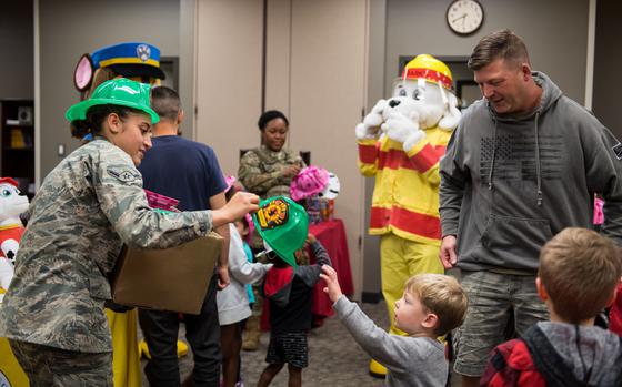 Airman Alexandra Nowak, 2nd Civil Engineer Squadron firefighter, hands a plastic fire helmet to a child during the Exceptional Family Member Program’s Dinner with Sparky at Barksdale Air Force Base, Louisiana, Oct. 11, 2019. The night was dedicated to giving children in EFMP a chance to meet with first responders. (U.S. Air Force photo by Airman 1st Class Lillian Miller)