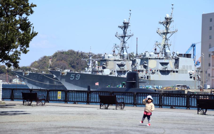 A child plays in a park across from the guided-missile destroyers USS. John S. McCain, left, and USS Russell at Yokosuka Naval Base, Japan, April 14, 2020.