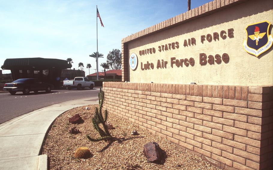 A close-up view of the Luke Air Force Base sign with the main gate in the background.