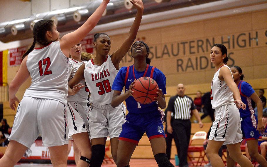 Ramstein's Javionne Jones goes up for a shot in the key as Raiders, from left, Katya von Eicken and Hazel Sanders defend during a Dec. 14, 2023, game at Kaiserslautern High School in Kaiserslautern, Germany.