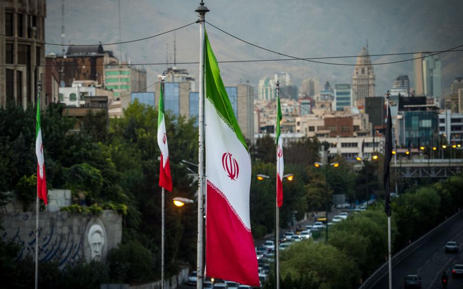 Iranian national flags fly near a highway.
