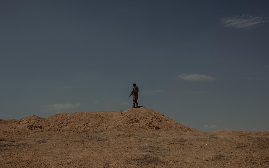 A member of the commandos unit of the Syrian Democratic Forces stands on a sand berm in the eastern part of Syria's Hasakah province during what was thought to be a security threat on the road between Raqqa and Dashisha on Aug. 3. 