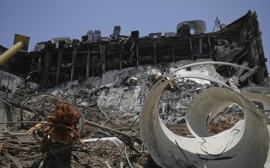 Debris is piled in front of a severly damaged multi-story building.