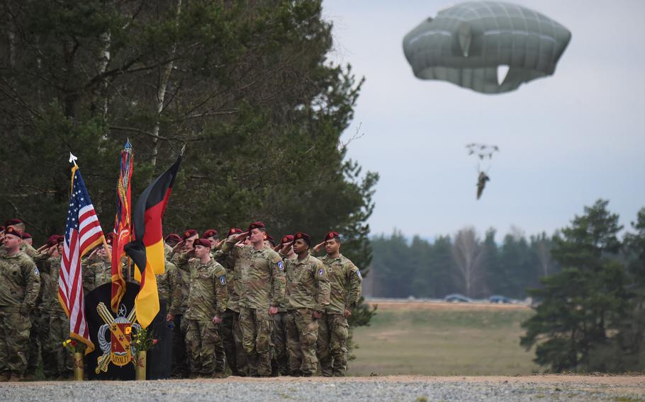 Members of the 319th Airborne Field Artillery Regiment salute in formation while paratroopers complete their jump during the opening moments of the drop zone renaming ceremony in honor of Cpl. Emmanuel Hernandez at Grafenwoehr, Germany, on April 20, 2023.