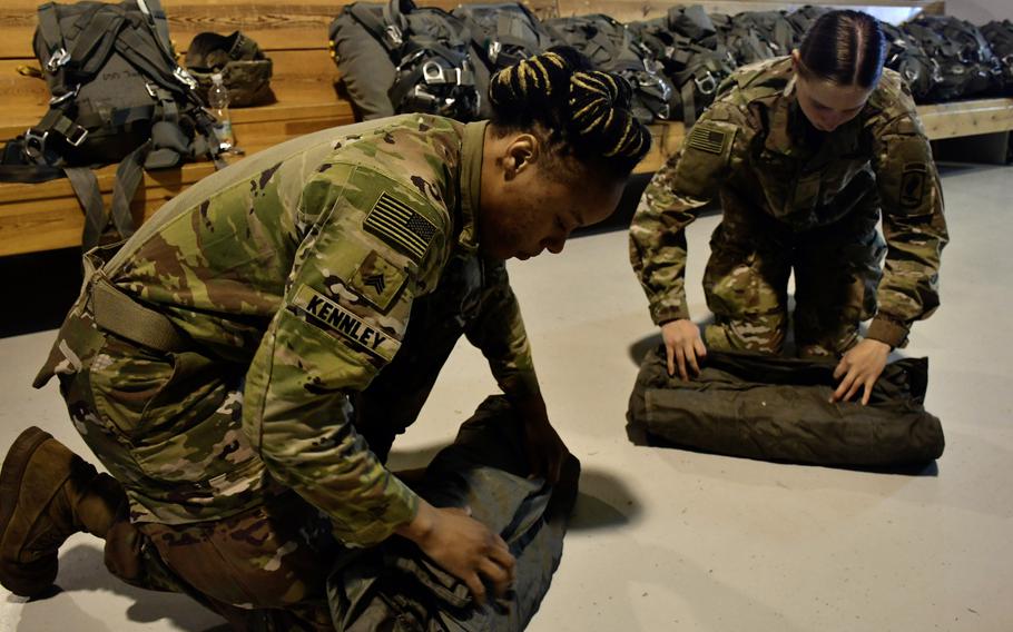 Two U.S. Army paratroopers fold their parachute retrieval bags.