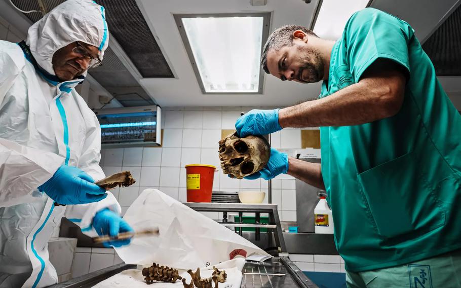 Volunteer Jean Loup Gassend, 41, right, examines human remains recovered from Israeli communities near the Gaza Strip border that were attacked by Hamas militants.
