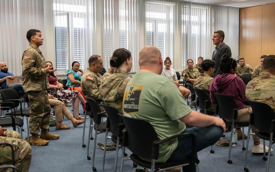 A soldier speaks with former Sgt. Maj. of the Army Daniel Dailey during a town hall meeting at Sembach Kaserne, Germany, June 22, 2023.