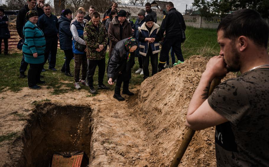Mourners at Andriy’s funeral toss dirt onto his grave as the service concludes.