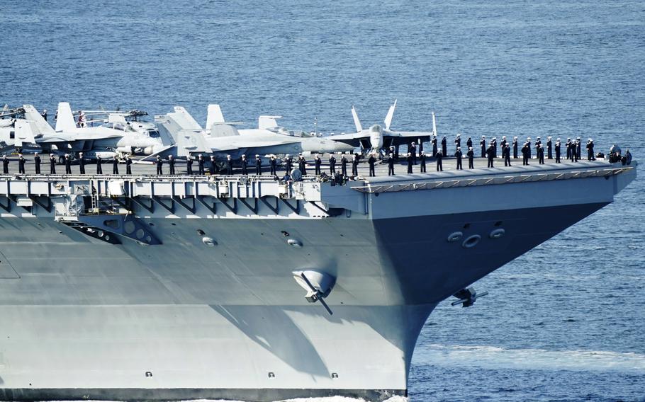 The crew of the aircraft carrier USS Gerald R. Ford stands on the flight deck as the carrier passes on its way into the Oslo Fjord, at Drobak, Norway, Wednesday, May 24, 2023. The ship is the world's largest warship and will be in port of Oslo for four days. 