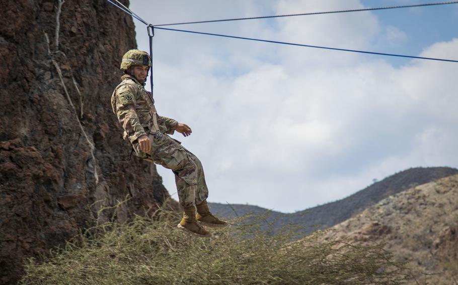 Staff Sgt. Elijah Amendola, 1-102nd Infantry Regiment (Mountain), Task Force Iron Gray, Combined Joint Task Force  Horn of Africa, utilizes a method French service members use for descending a mountain at the Arta Range Complex, Djibouti, Dec. 16, 2021. Instructors from the U.S. Army Mountain Warfare School exchanged basic military mountaineering skills with French service members in Djibouti.