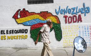 A man walks in front of a mural of the Venezuelan map with the Essequibo territory included, in Caracas, Venezuela, Wednesday, Nov. 29, 2023. Venezuelans will attempt to decide the future of the Essequibo territory, a large swath of land that is administered and controlled by Guyana but claimed by Venezuela, via a referendum that the Venezuelan government put forth in its latest attempt to claim ownership, saying it was stolen when a north-south border was drawn more than a century ago. (AP Photo/Matias Delacroix)