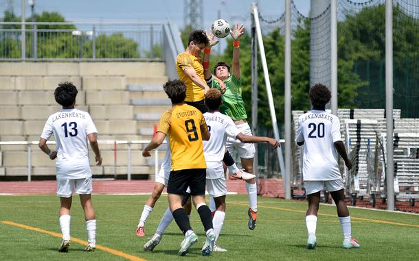 Lakenheath goalkeeper Matthew Vasquez and Stuttgart striker Seth Harpuder jump for a ball during a Division I semifinal match at the 2025 DODEA European championships on May 21, 2025, at Kaiserslautern High School in Kaiserslautern, Germany.