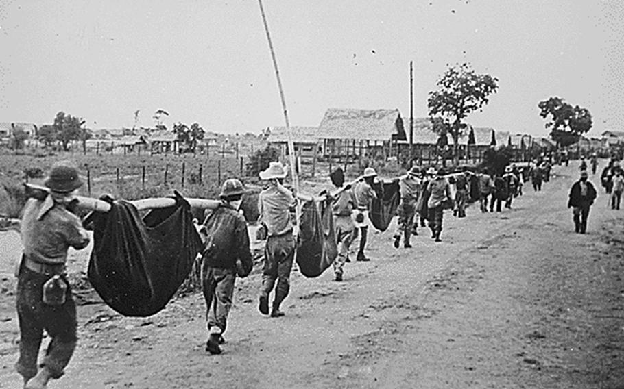 American and Filipino prisoners of war carry dead comrades after the Bataan Death March in May 1942.