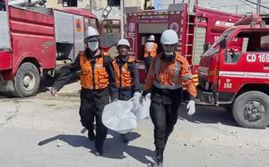 Masked workers carry body bags.