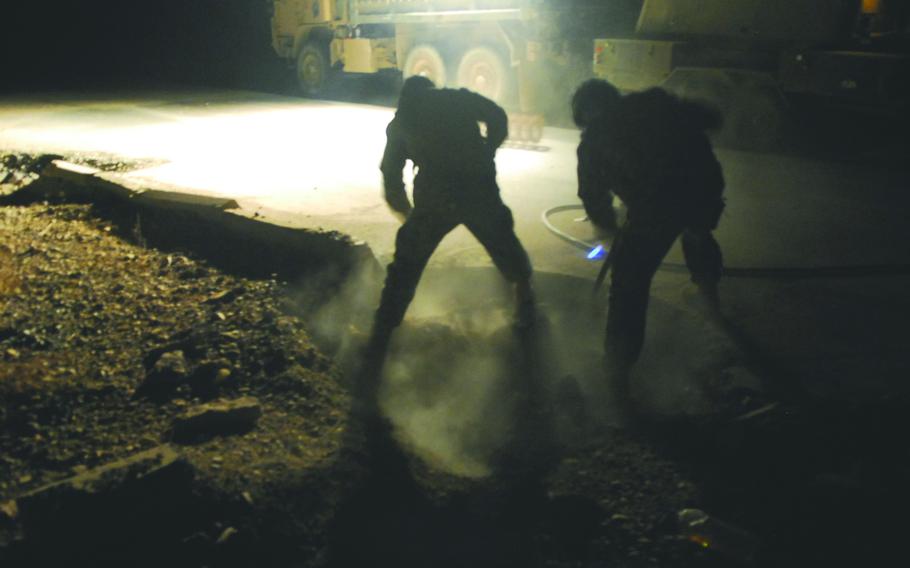 Soldiers with the 60th Engineering Company, who are attached to the 19th Engineer Battalion, shovel debris from a roadside bomb crater before filling it with concrete along Highway One, near Tikrit, Iraq. If left unrepaired, the craters provide hiding places for explosives and driving hazards for motor vehicles.