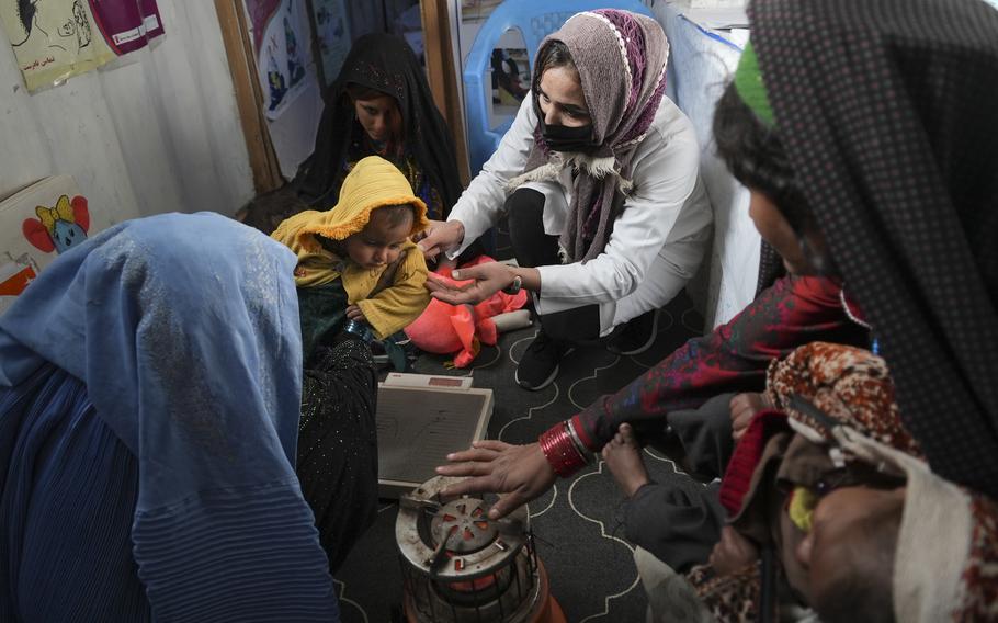 A nurse checks the weight of a child in a makeshift clinic organized by World Vision at a settlement near Herat, Afghanistan, Dec. 16, 2021.