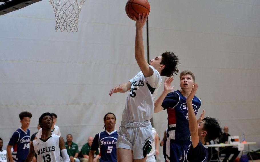 Naples’ Jettyn Jones gets past Aviano’s Aiden Haas and Joseph Guerrero for a basket in a Division II semifinal at the DODEA-Europe basketball championships in Ramstein, Germany, Feb. 17, 2023. Naples beat Aviano 68-49 to advance to Saturday’s final against AOSR.